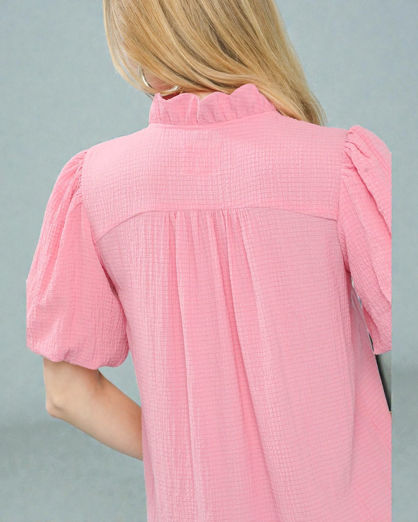 Pink textured dress worn by a person on a gray background