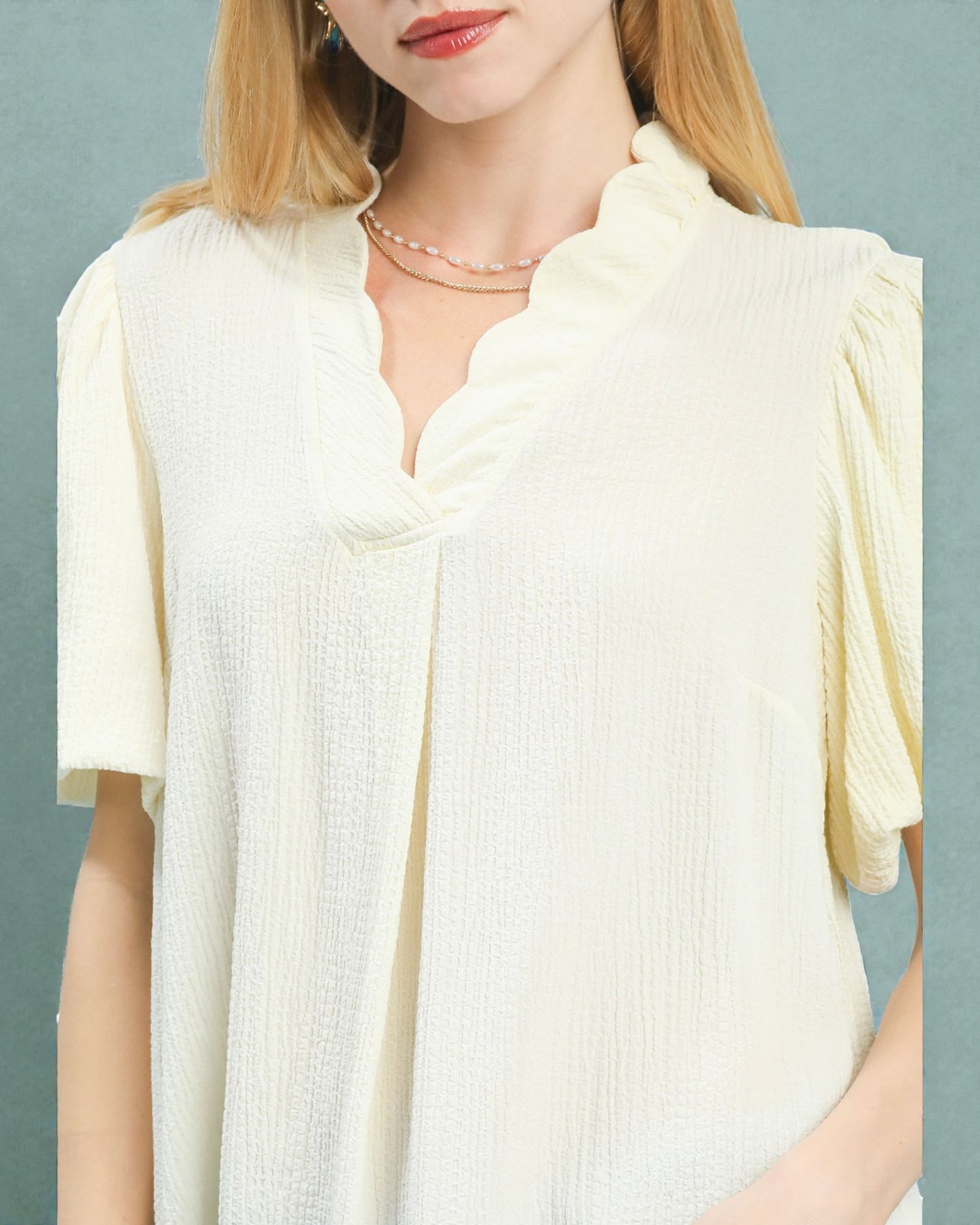 Woman wearing a light yellow short-sleeve top against a gray background