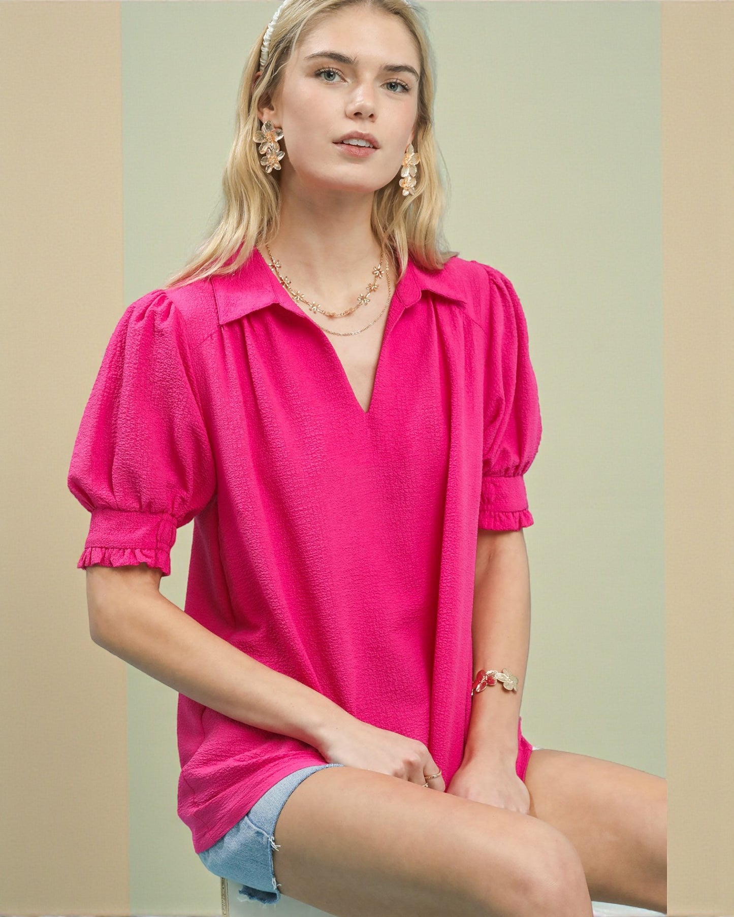 Woman wearing a bright pink blouse with puff sleeves against a neutral background
