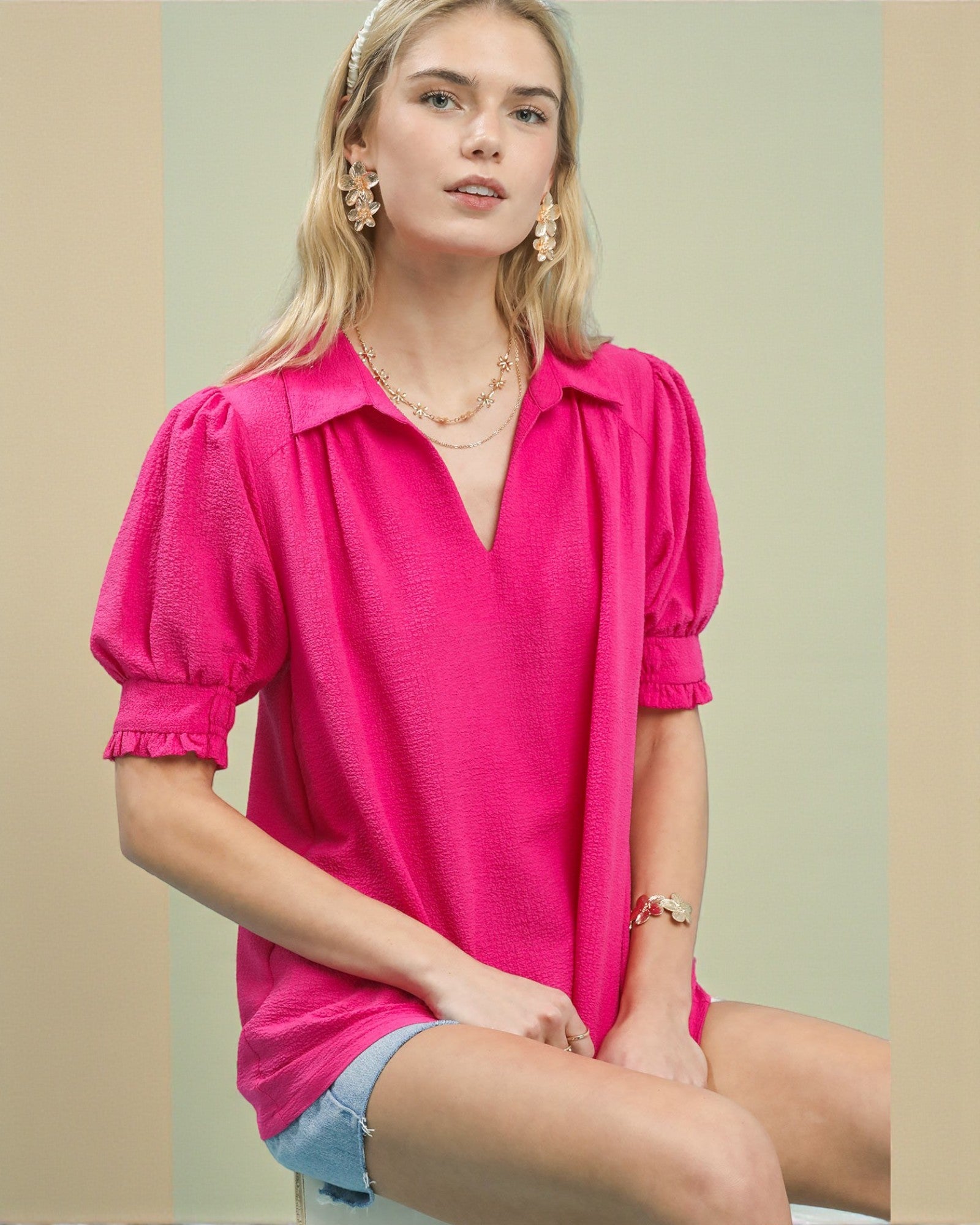 Woman wearing a bright pink blouse with puff sleeves against a neutral background