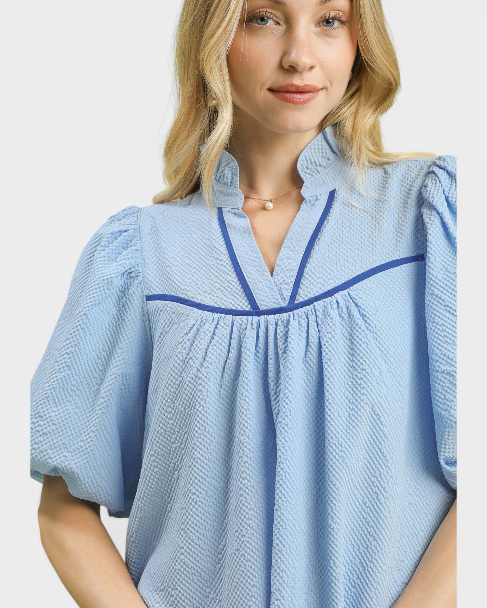 Woman wearing a light blue blouse with a white background