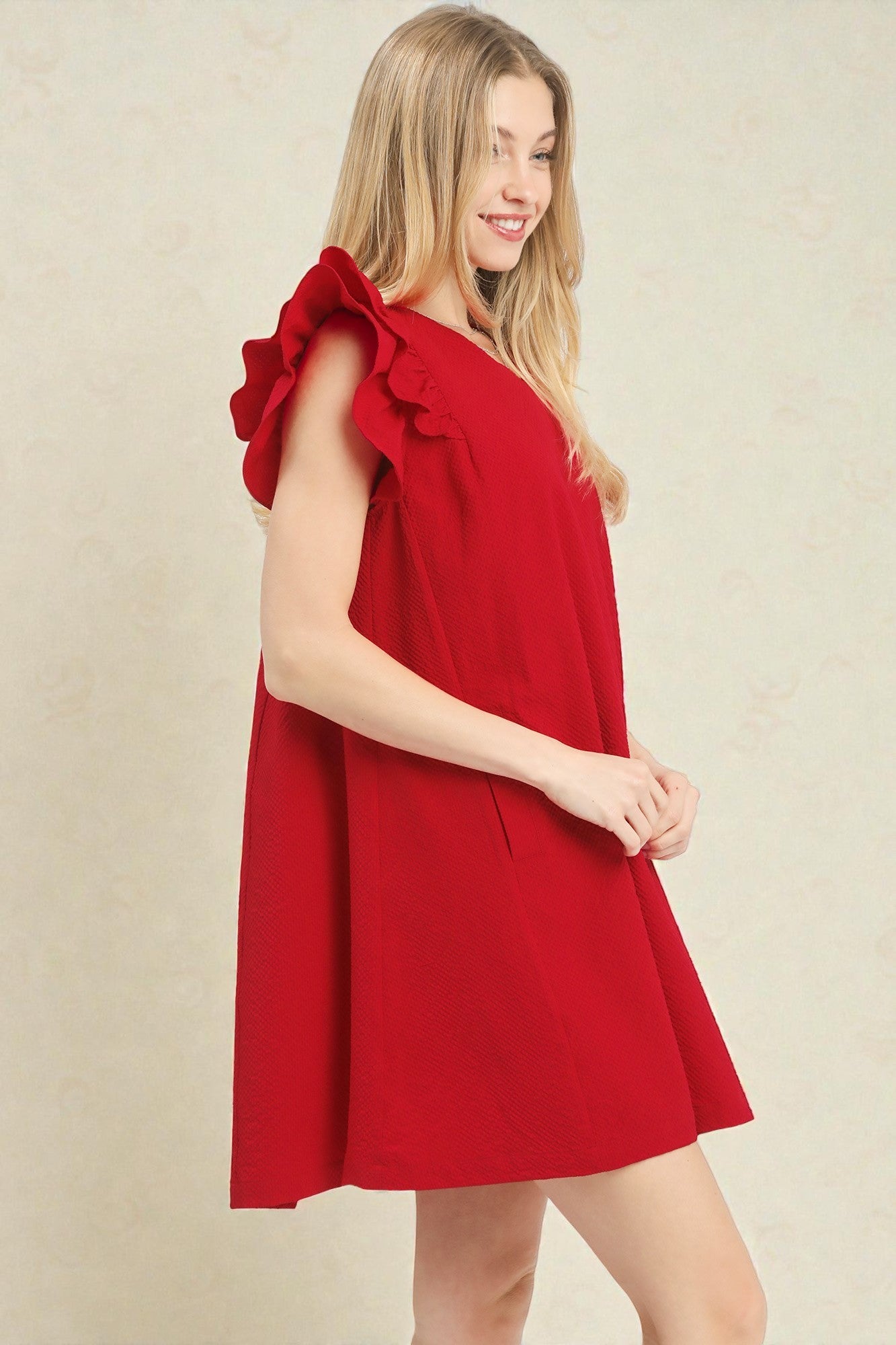 Woman wearing a red dress with ruffled sleeves on a beige background