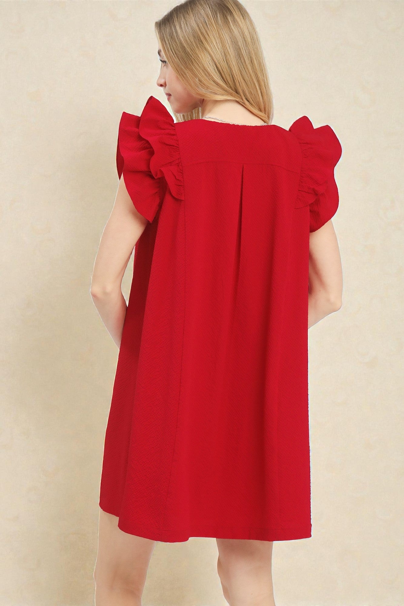Red dress with ruffled sleeves on a beige background