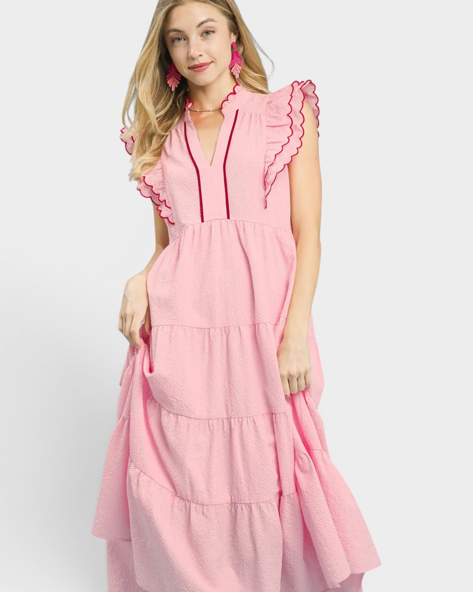 Woman wearing a pink dress with ruffled details on a white background