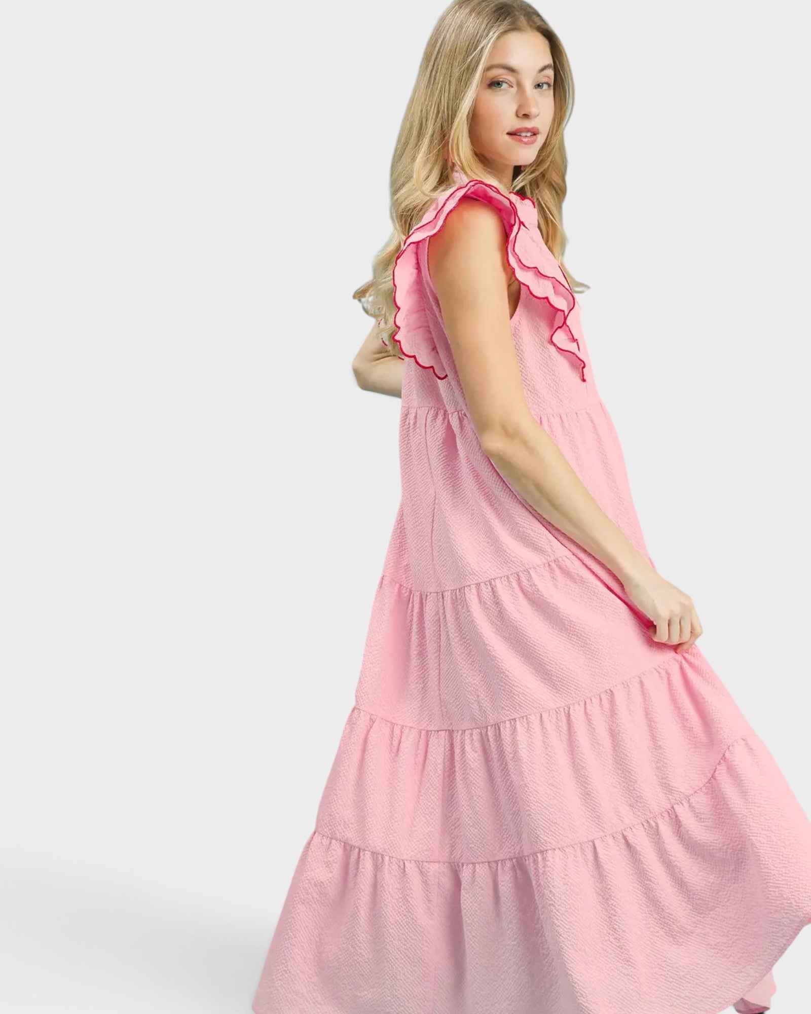 Woman wearing a pink dress with ruffled sleeves on a white background