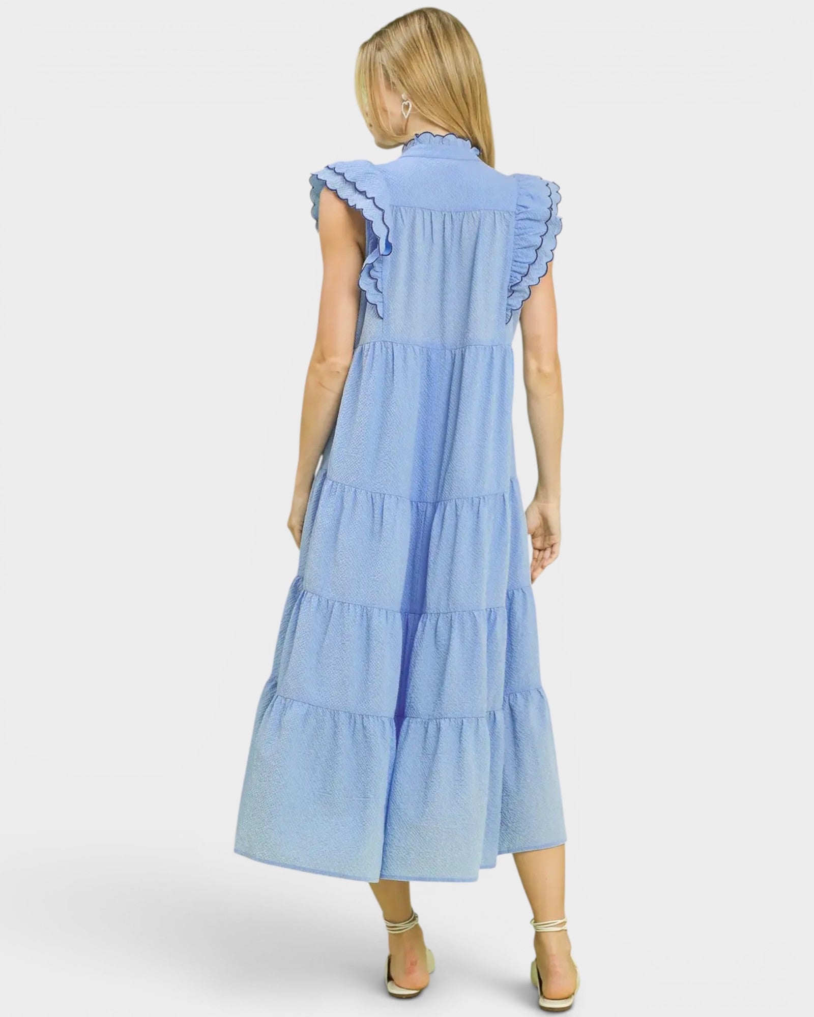 Woman wearing a light blue dress with ruffled sleeves on a white background