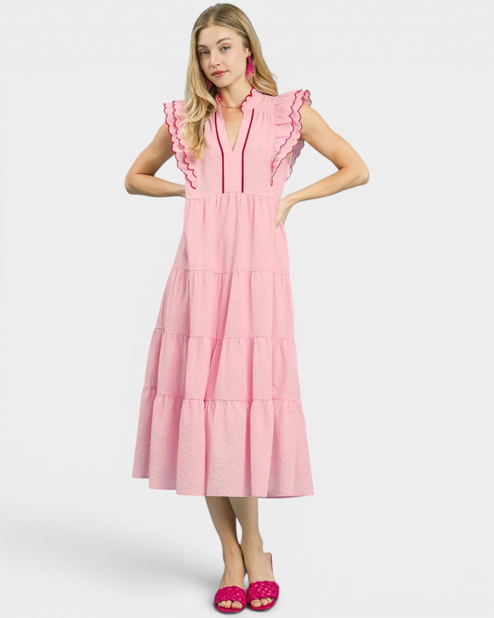 Woman wearing a pink dress with ruffled details on a white background