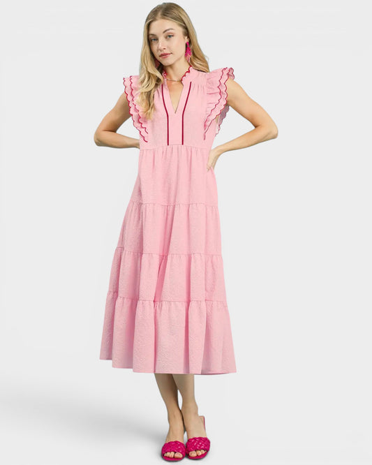 Woman wearing a pink dress with ruffled details on a white background