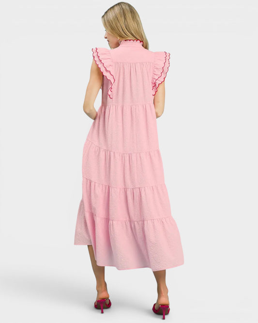 Woman wearing a pink dress with ruffled details on a white background