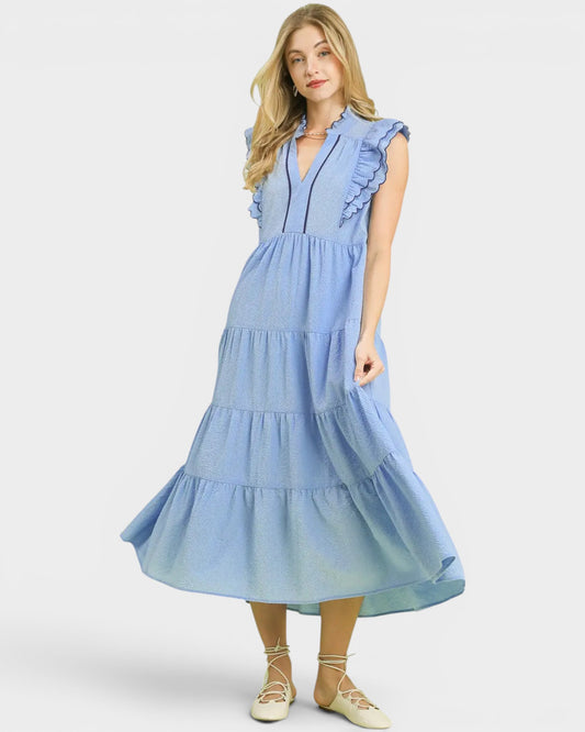 Woman wearing a blue dress with ruffled sleeves and tiered skirt on a white background