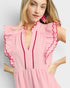 Woman wearing a pink dress with ruffled sleeves on a light gray background