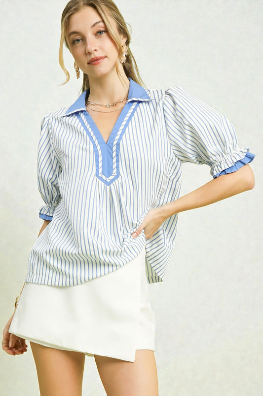 Woman wearing a striped shirt with blue accents and a white skirt on a plain background