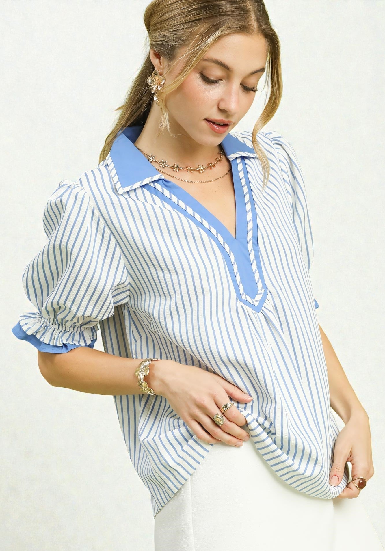 Woman wearing a blue and white striped shirt with a collar on a white background