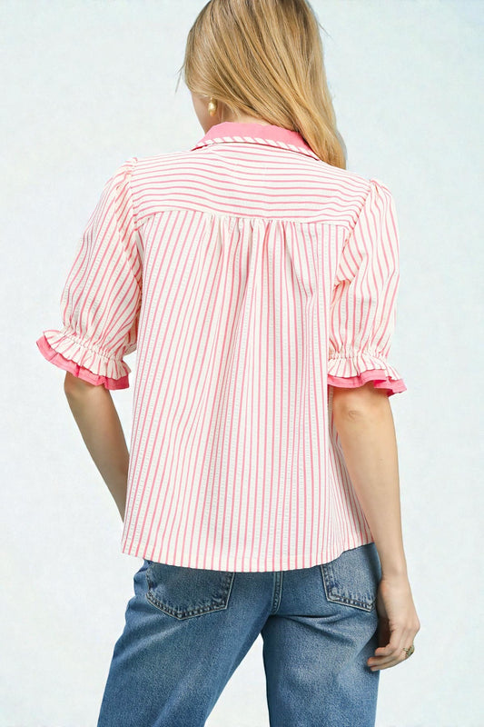 Person wearing a pink and white striped shirt with rolled-up sleeves on a plain background