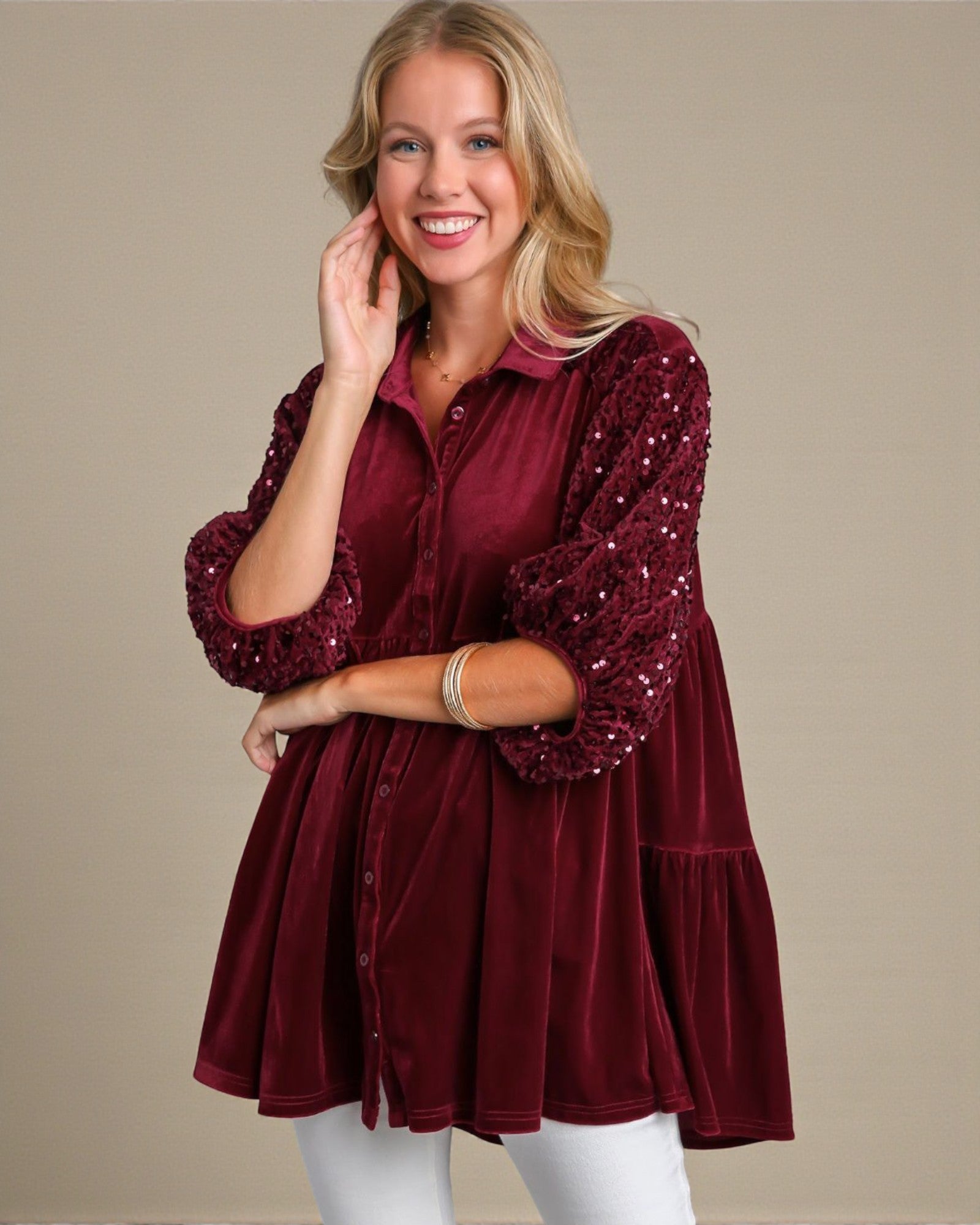 Woman wearing a burgundy sequin blouse against a beige background
