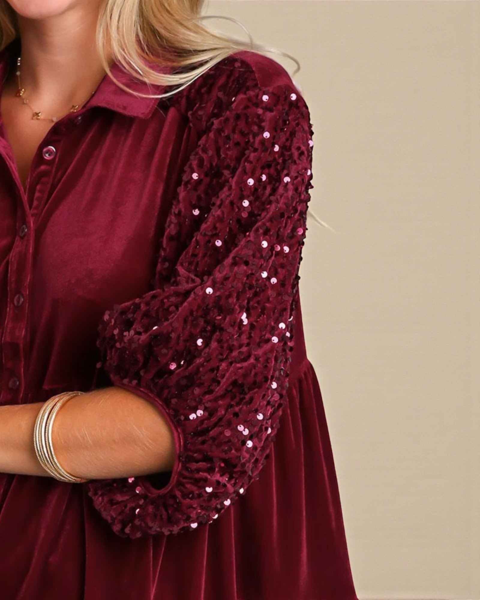 Burgundy velvet dress with sequin sleeves on a beige background