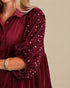 Burgundy velvet dress with sequin sleeves on a beige background
