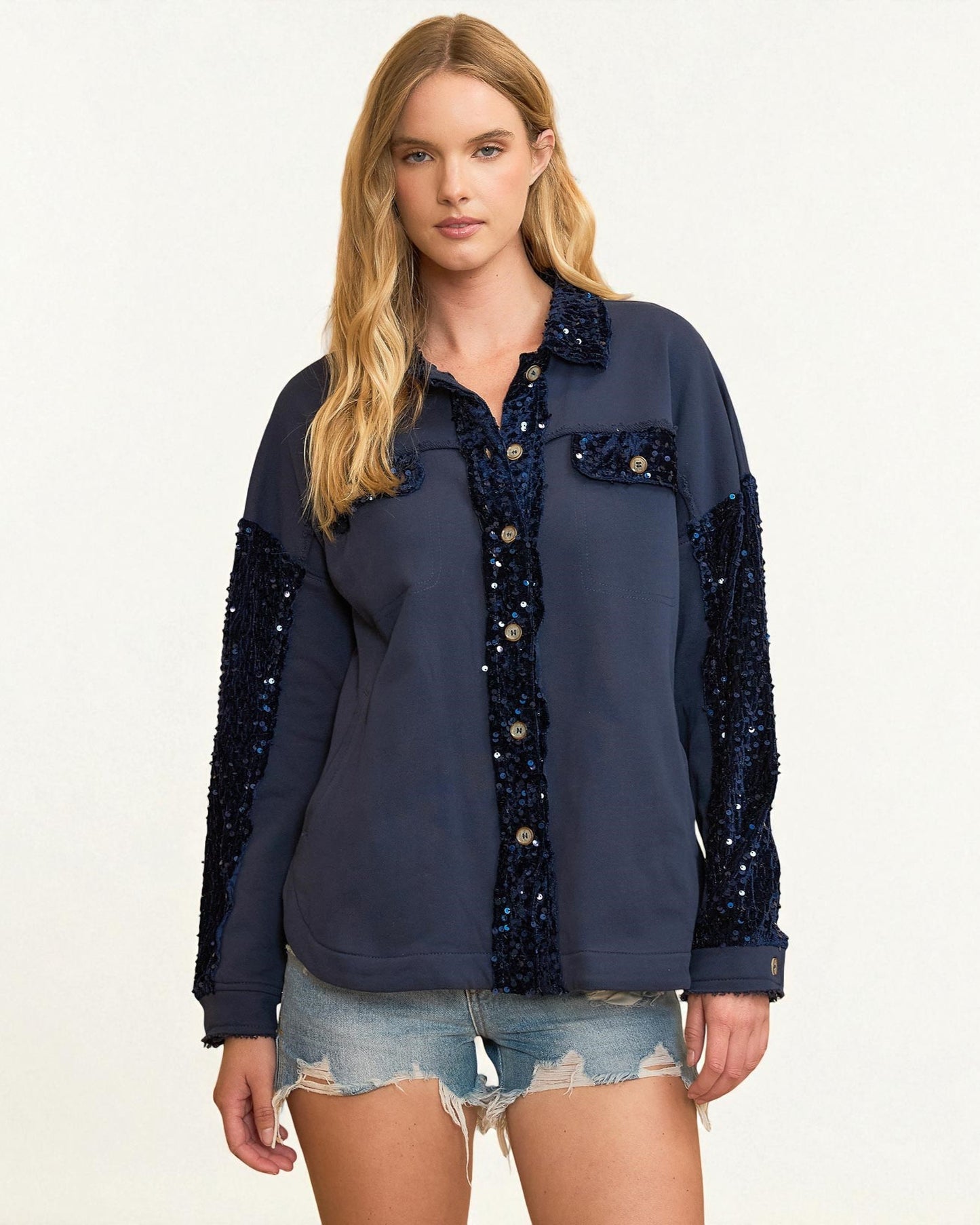 Woman wearing a navy blue shirt with sequin details on a white background