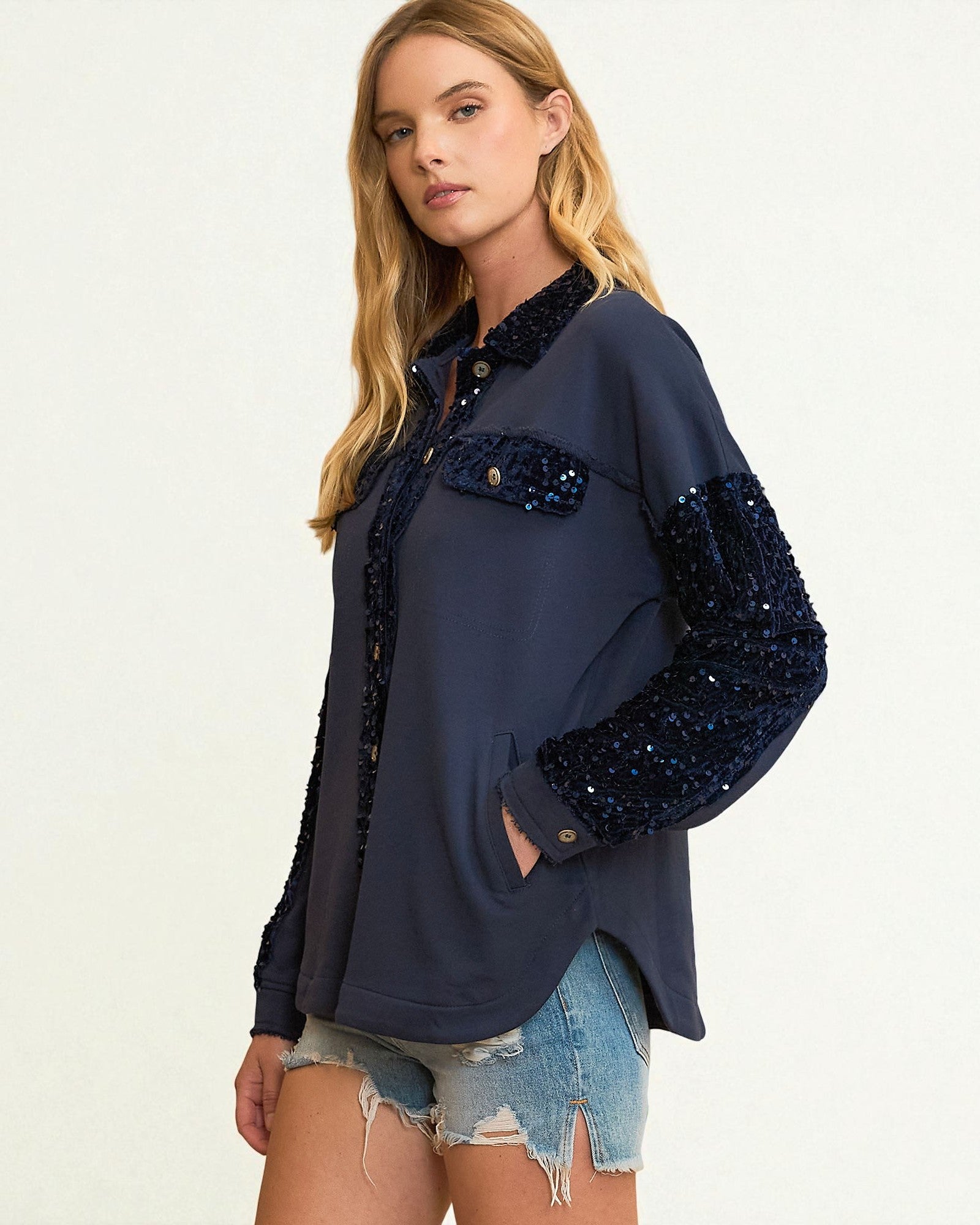 Woman wearing a navy blue sequin jacket on a white background