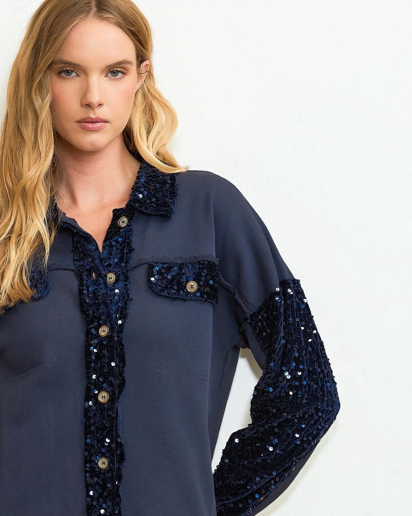 Woman wearing a navy blue shirt with sequin details on a white background