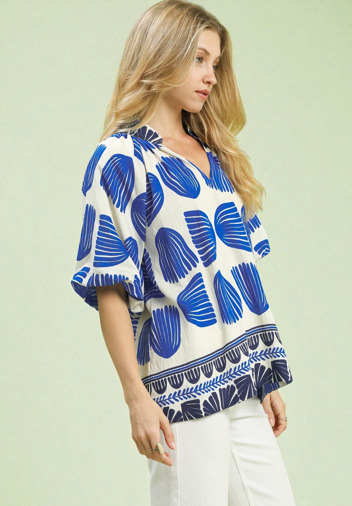 Woman wearing a blue and white patterned blouse on a light green background