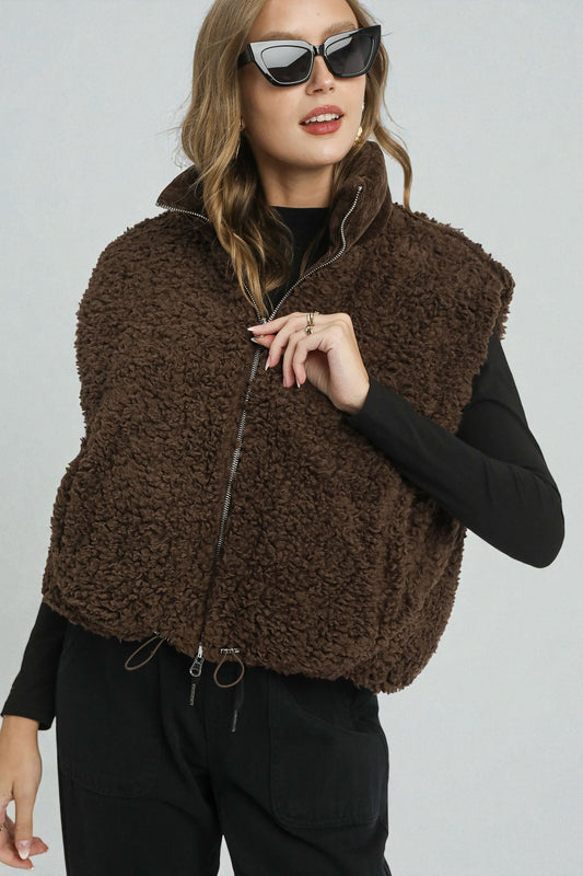 Woman wearing a brown fleece vest against a plain background