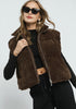 Woman wearing a brown fleece vest over a black outfit on a white background