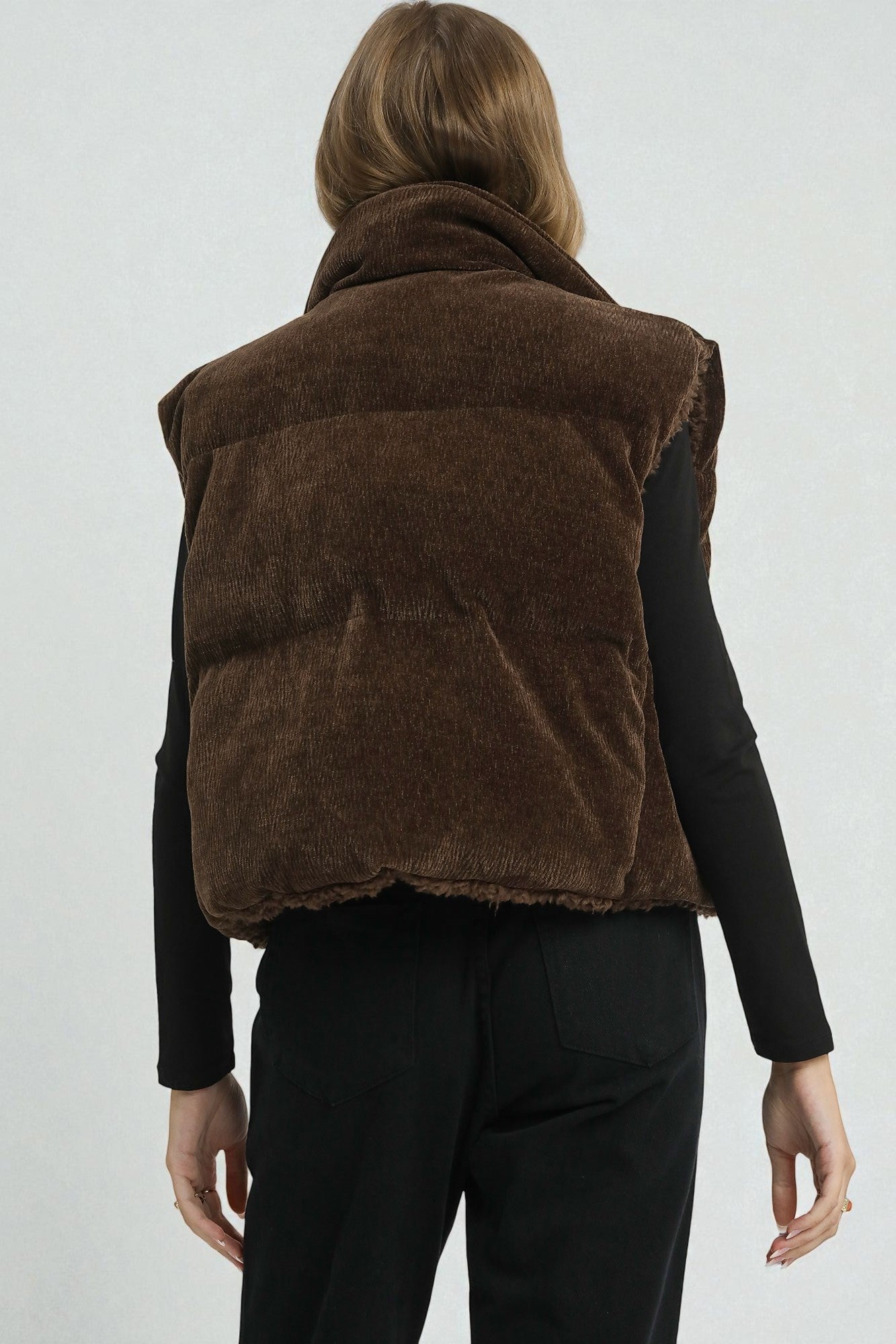 Brown puffer vest worn by a person on a white background