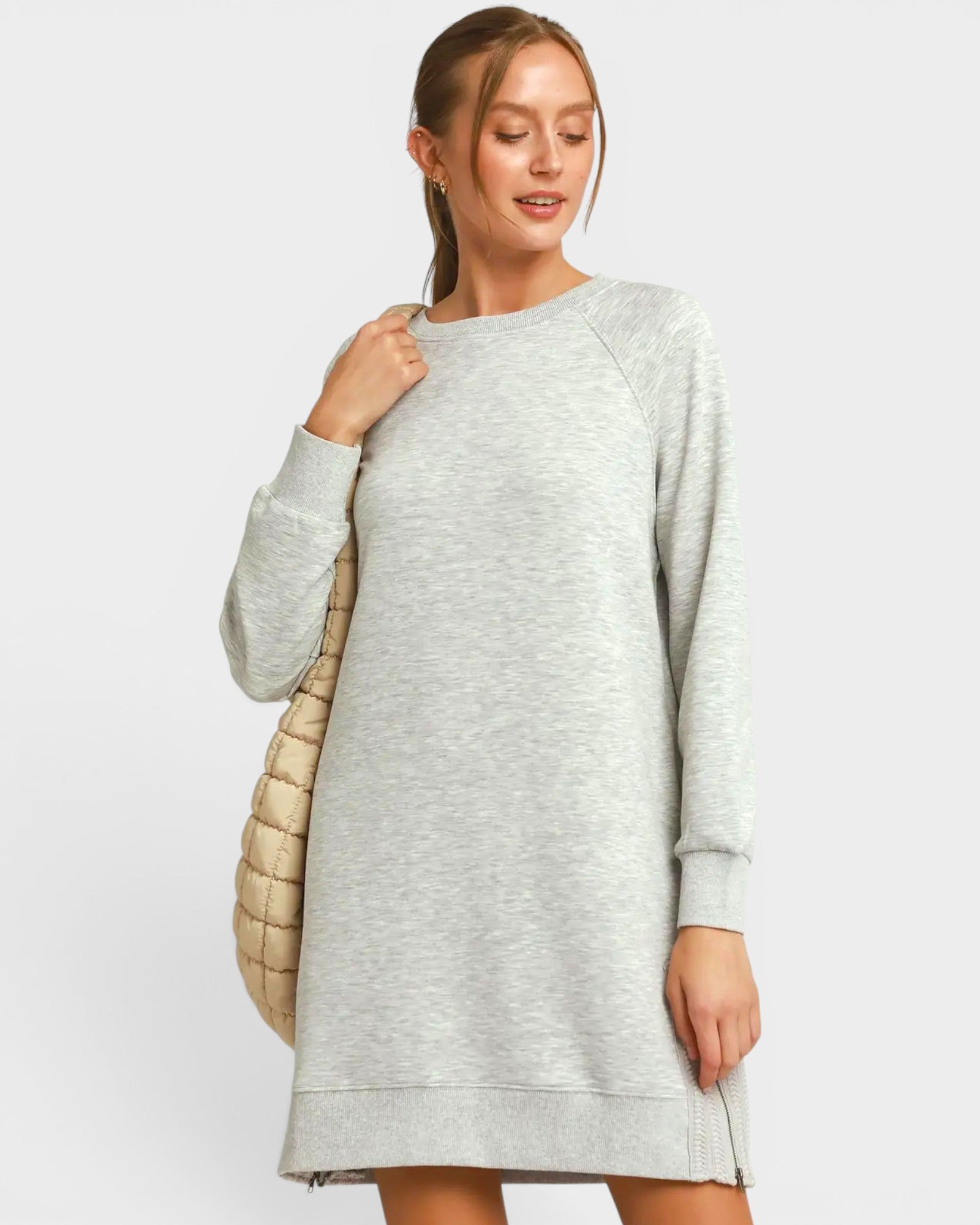 Woman wearing a gray sweater dress against a white background
