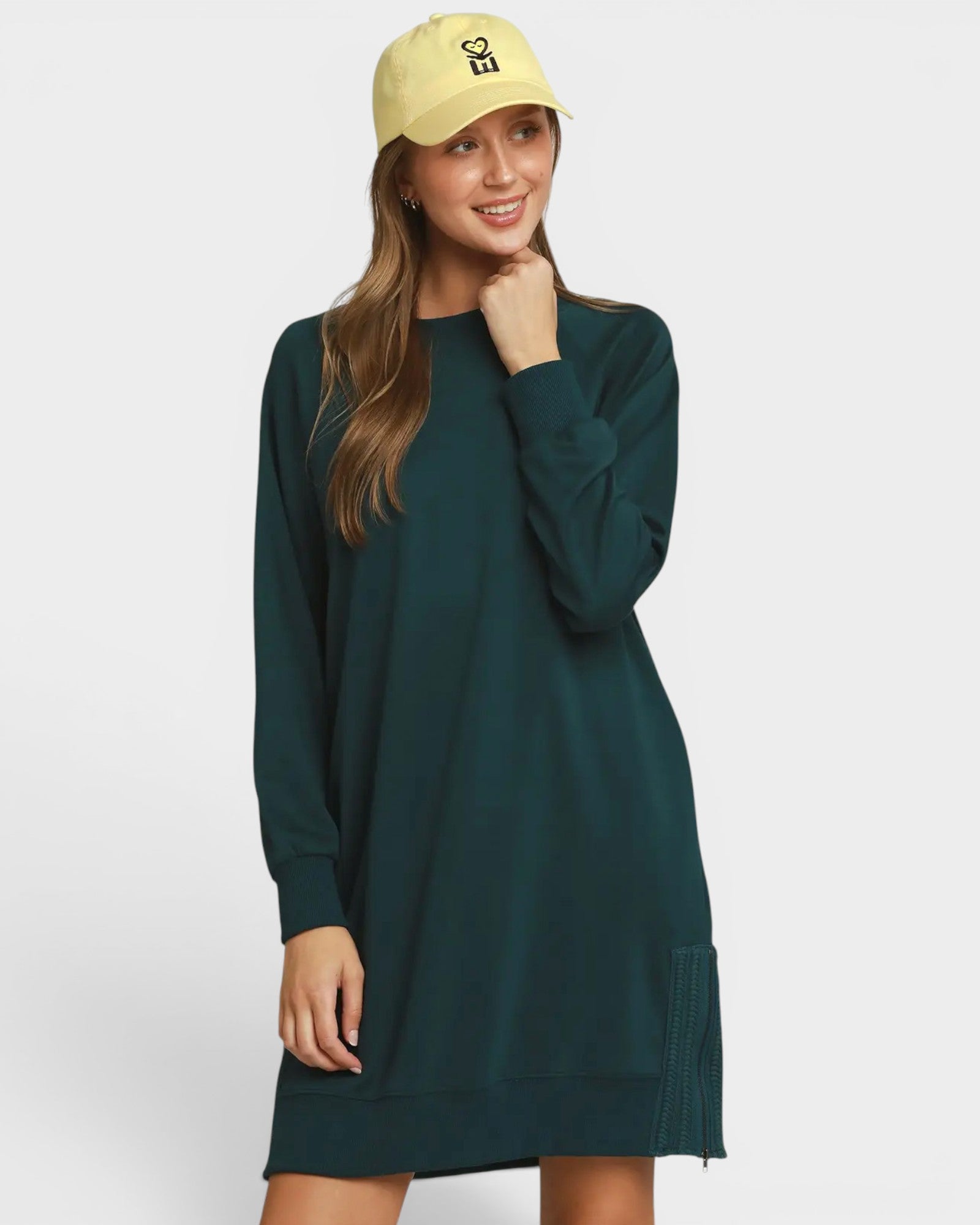 Woman wearing a green dress and yellow cap on a white background