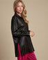 Woman wearing a black leather jacket over a pink dress on a beige background
