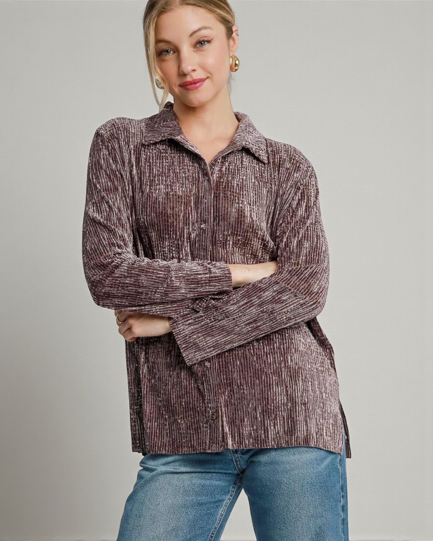 Woman wearing a brown textured shirt and blue jeans on a gray background