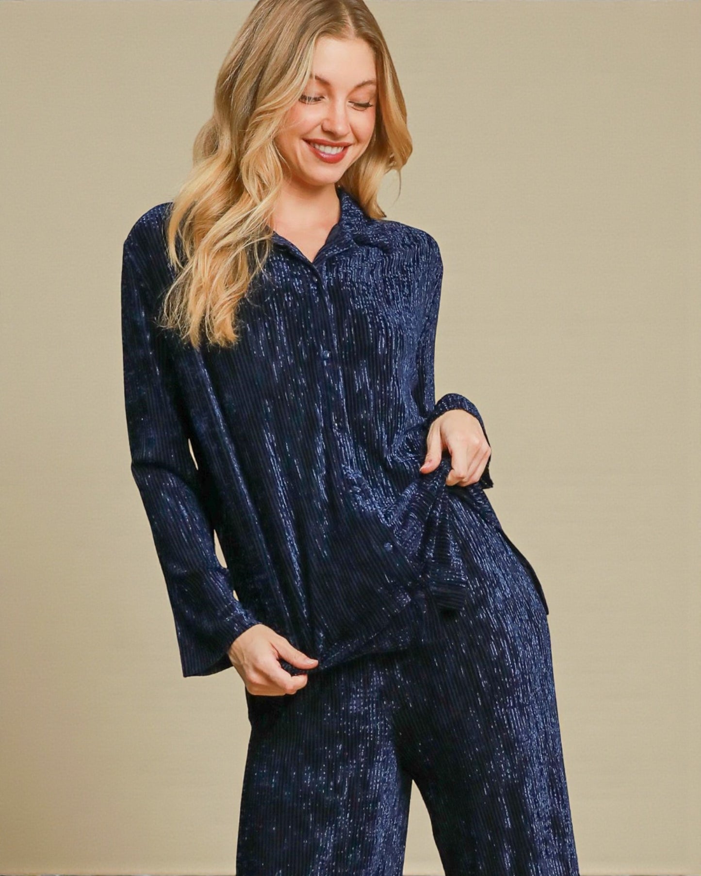 Woman wearing a navy blue velvet outfit on a beige background