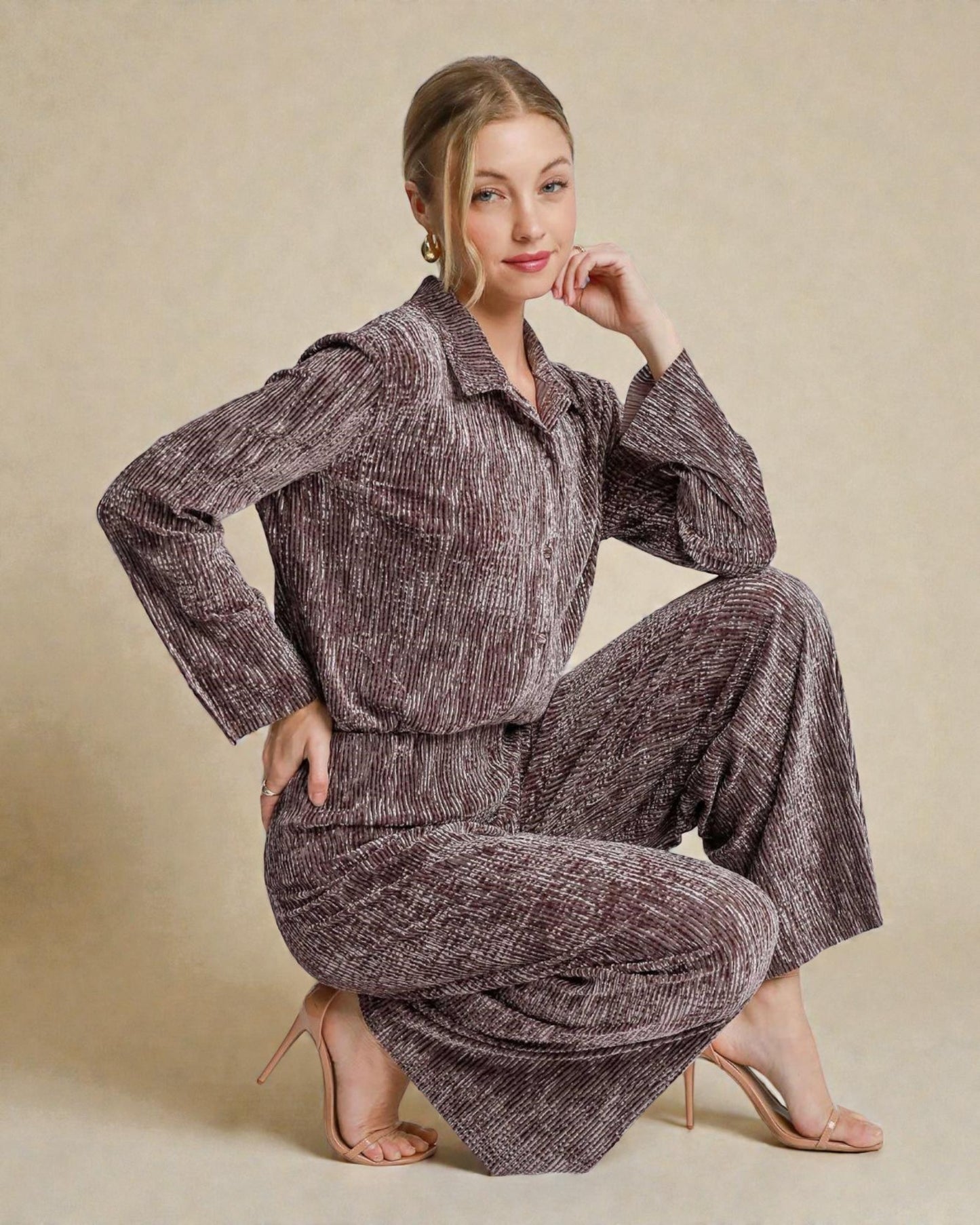 Woman wearing a textured brown outfit posing against a beige background