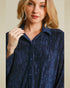 Woman wearing a blue textured shirt against a beige background