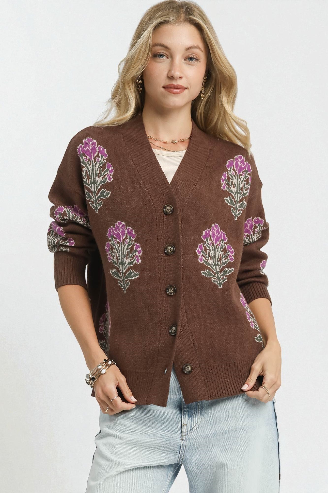 Woman wearing a brown cardigan with floral patterns on a white background