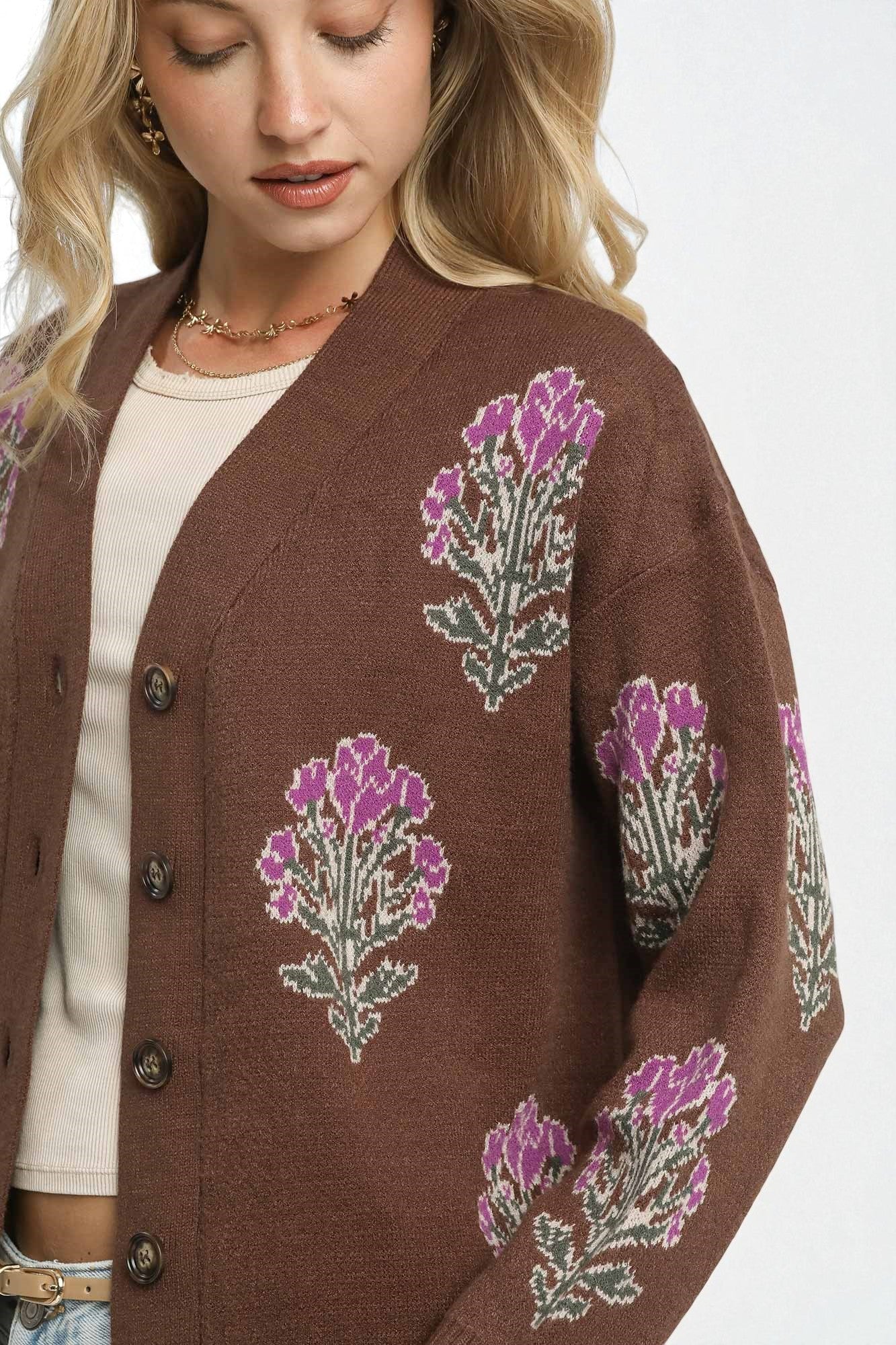 Brown cardigan with purple floral patterns worn by a person on a white background