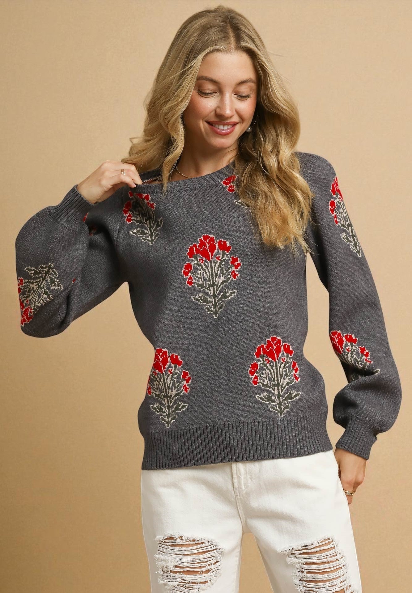 Woman wearing a gray sweater with floral patterns on a beige background