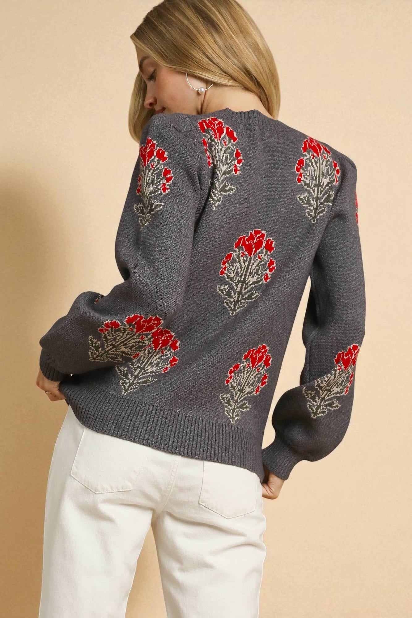 Woman wearing a gray sweater with red floral patterns on a beige background