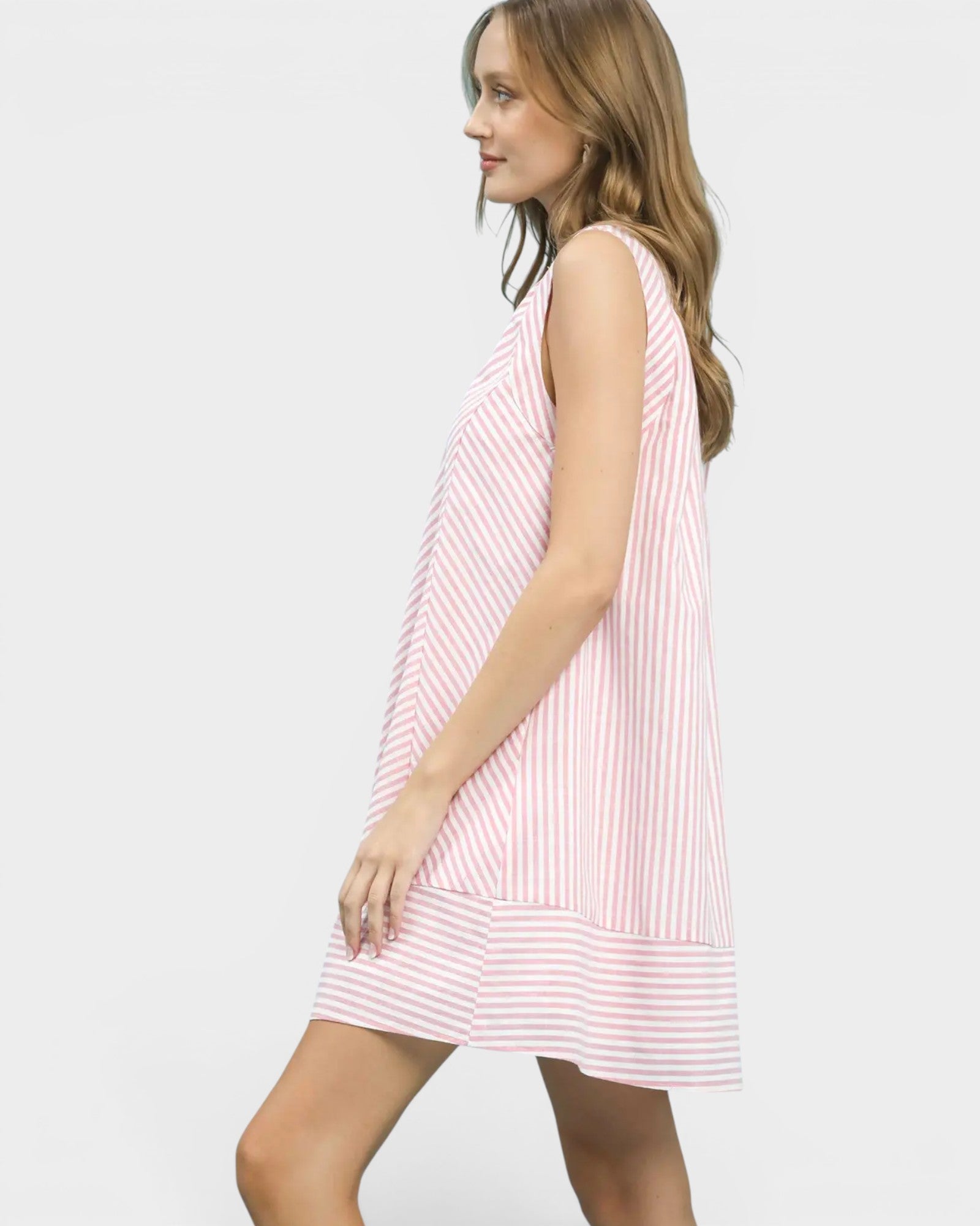 Woman wearing a pink and white striped dress on a plain background