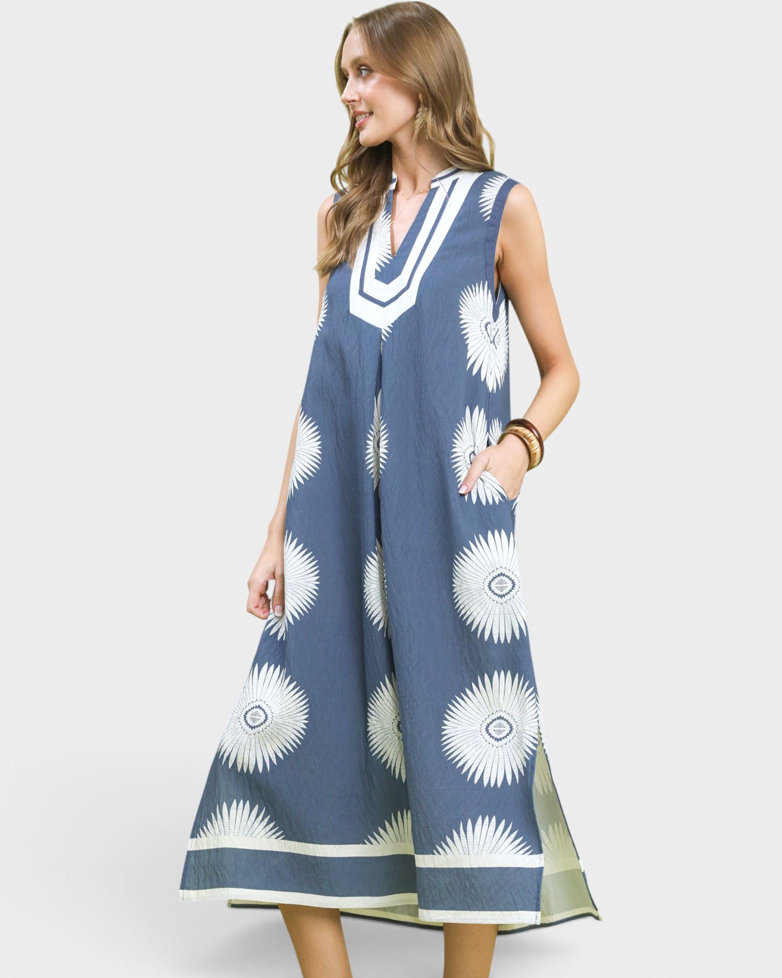 Woman wearing a blue dress with white floral patterns on a plain background