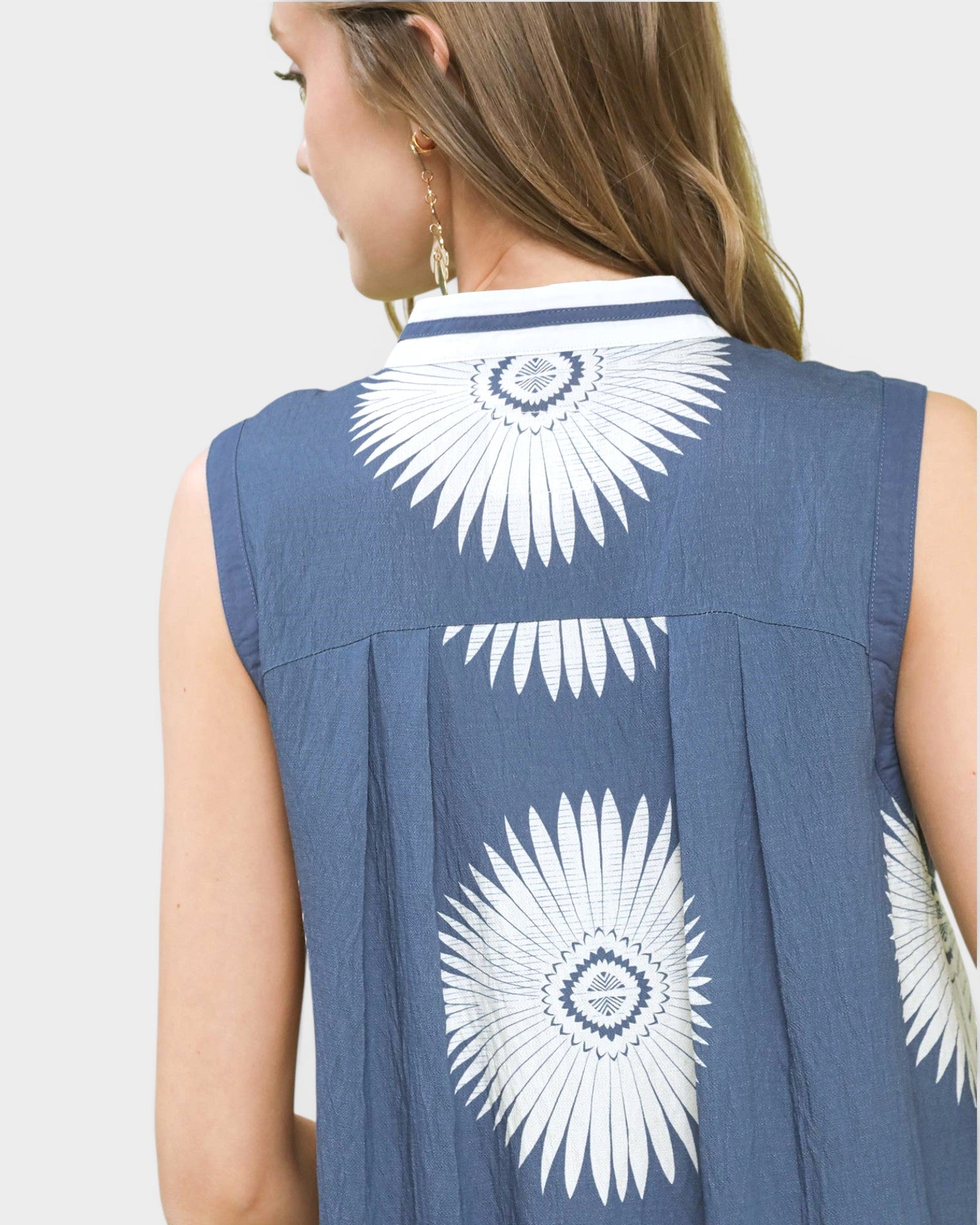 Blue sleeveless top with white floral patterns on the back against a light gray background