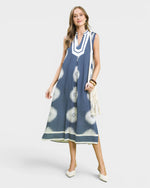 Woman wearing a blue dress with white patterns on a white background