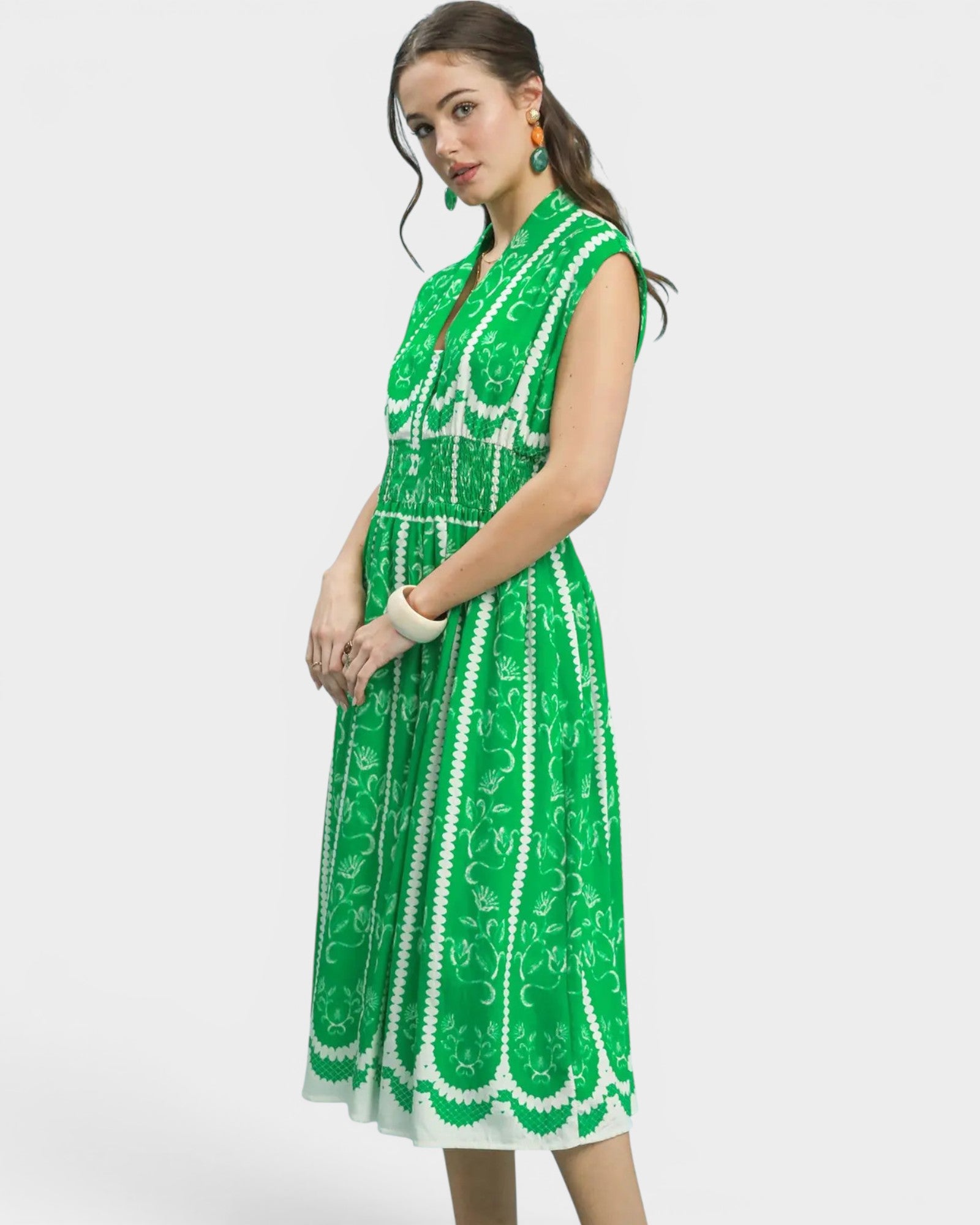 Woman wearing a green dress with white patterns on a white background