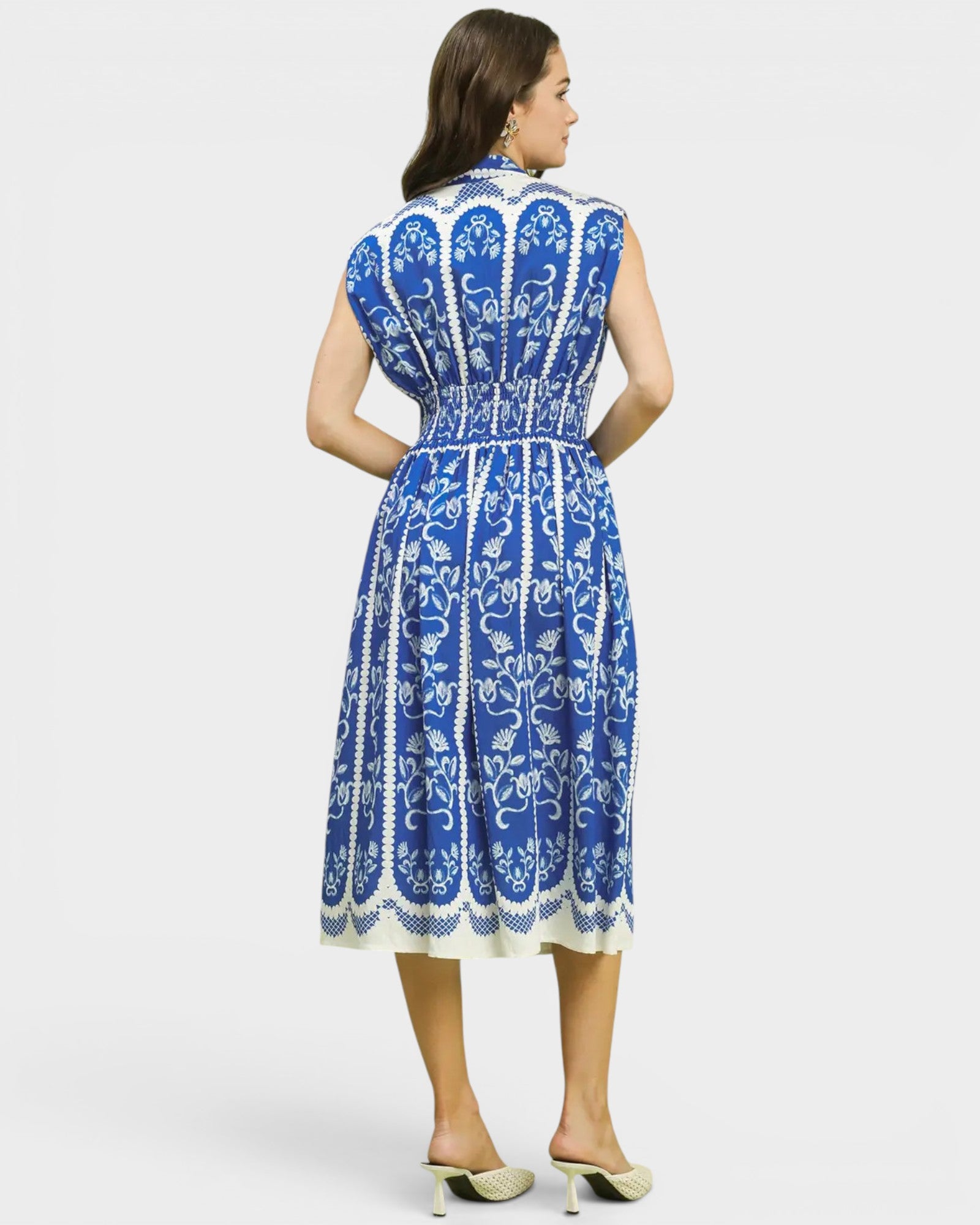 Woman wearing a blue and white patterned dress on a light gray background