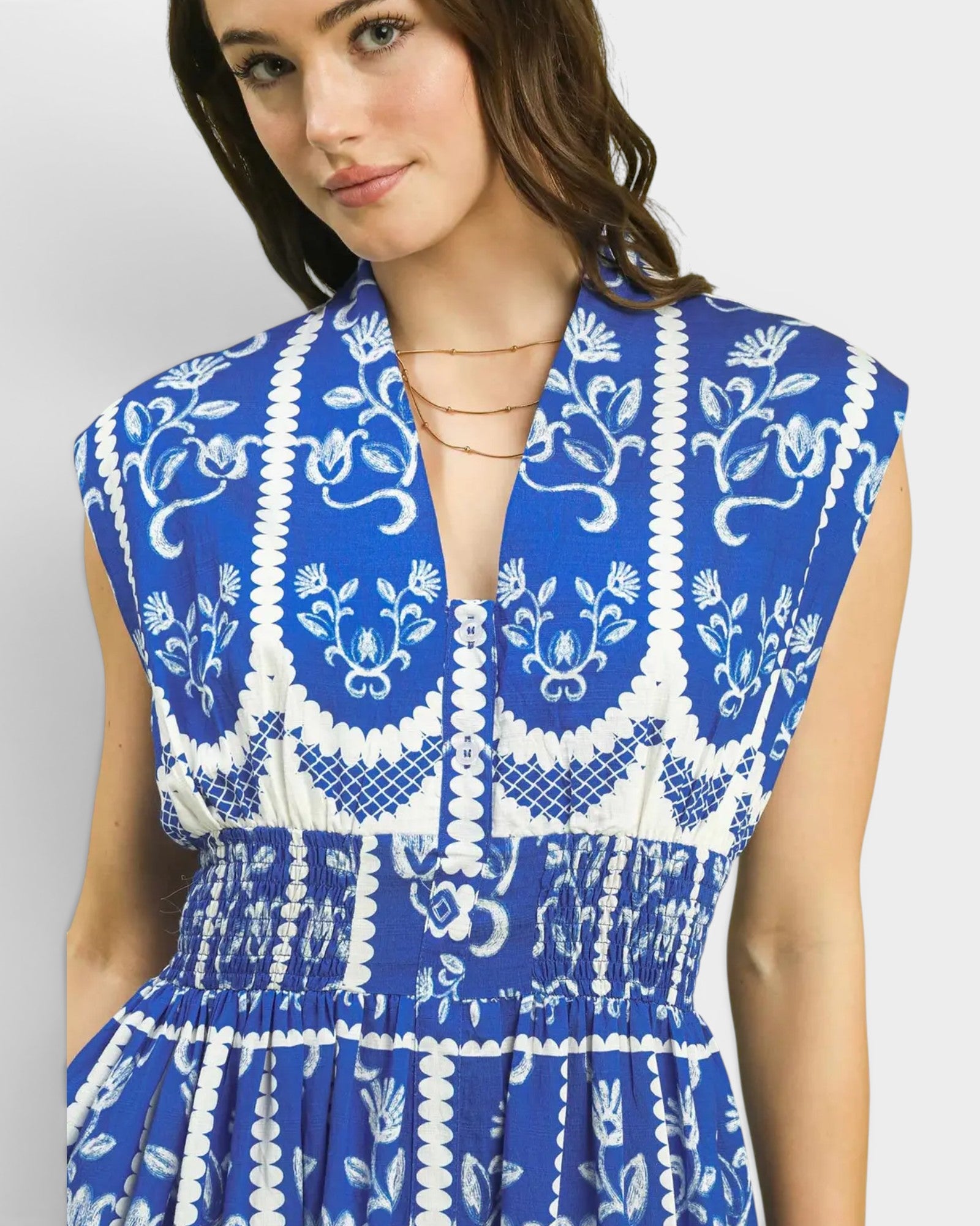 Woman wearing a blue and white patterned dress on a plain background