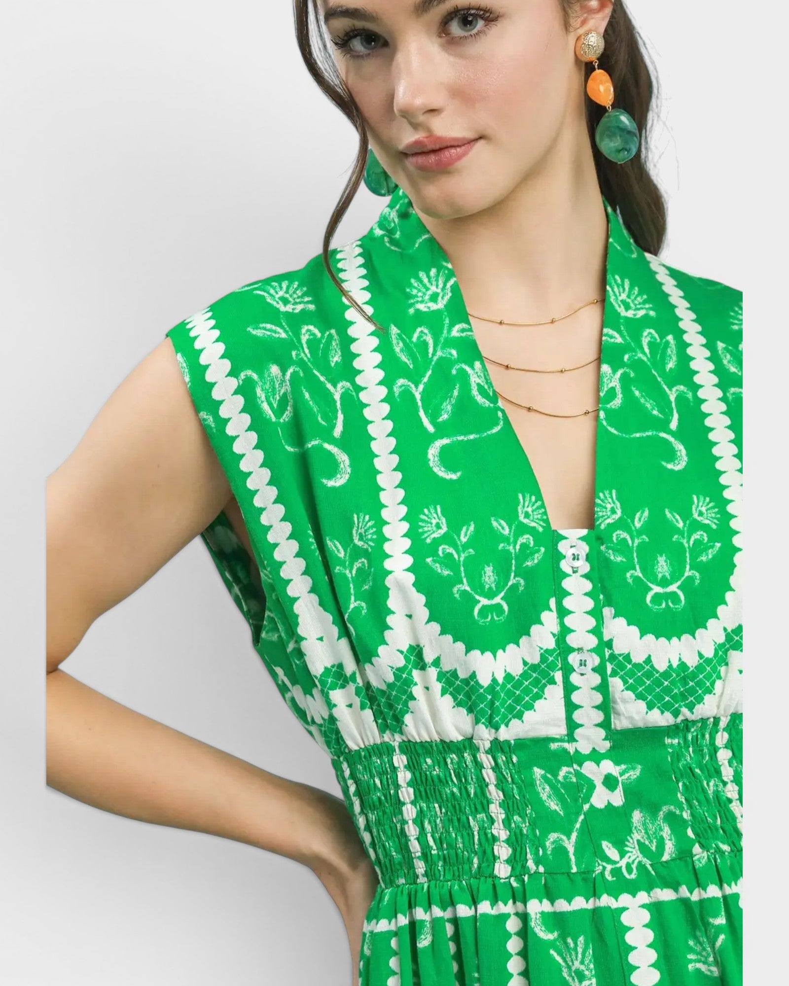 Woman wearing a green dress with white patterns on a plain background