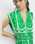 Woman wearing a green dress with white patterns on a plain background