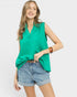 Woman wearing a green sleeveless top and denim shorts on a white background
