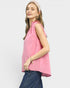 Woman wearing a pink sleeveless top and blue jeans on a white background